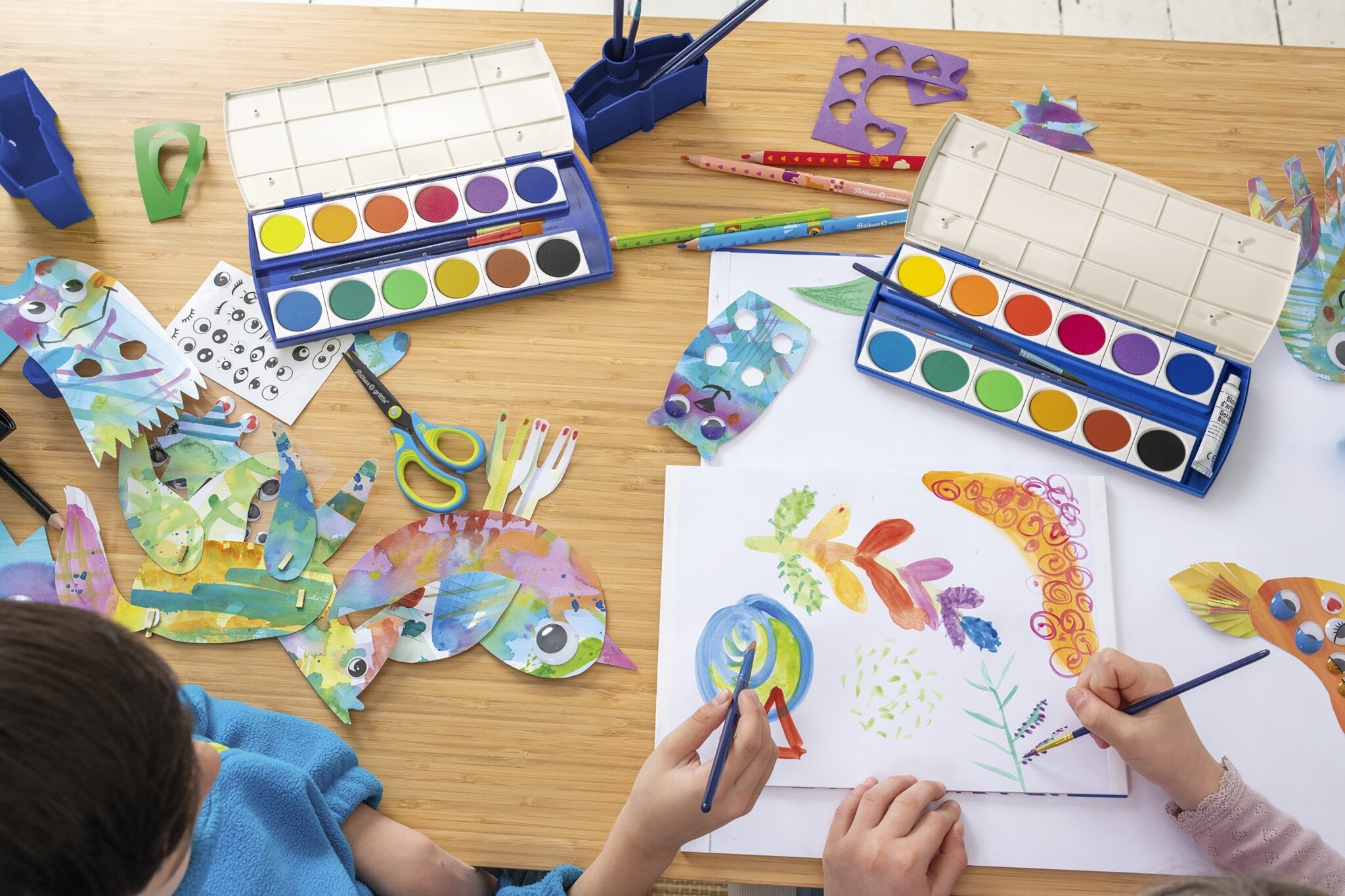 Ein junges Mädchen mit strahlendem Lächeln hält eine bunte Sammlung von Markern an die Brust und steht in einem gemütlichen Raum voller Bücher.