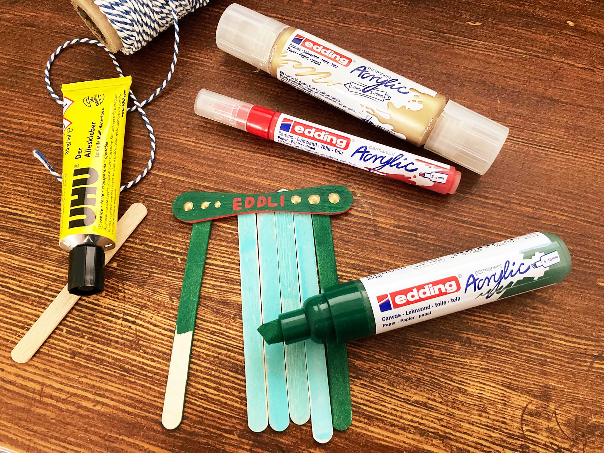 Bunte Eisstiele mit Acrylmarkern bemalt werden zu einer Wichteltür geklebt