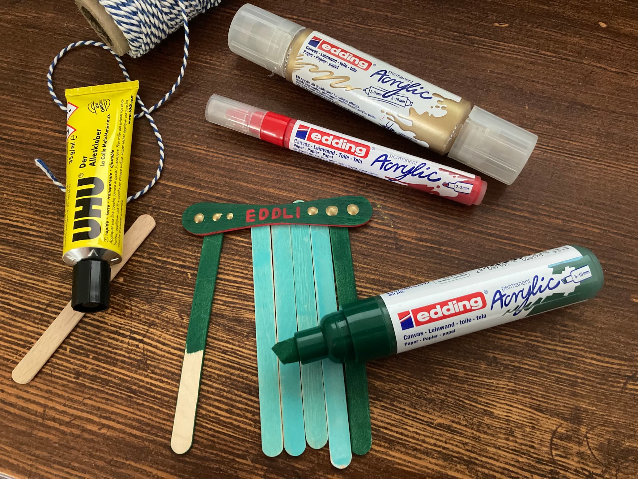 Bunte Eisstiele mit Acrylmarkern bemalt werden zu einer Wichteltür geklebt