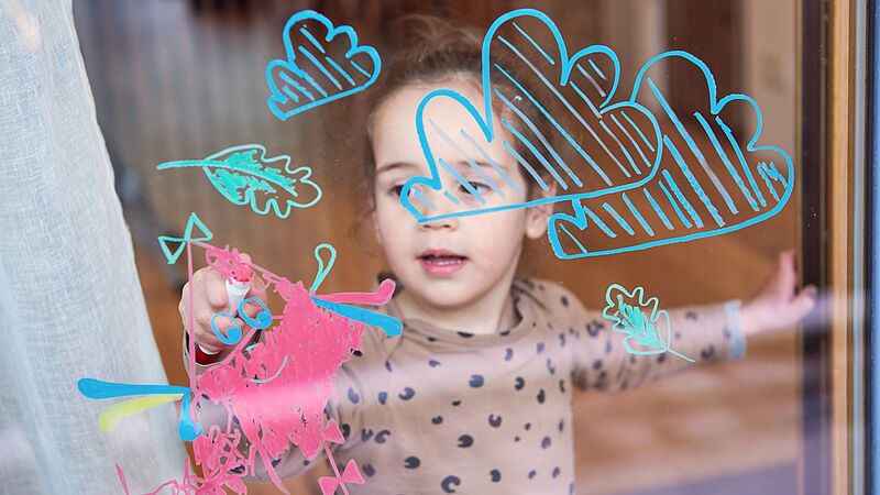 Mädchen malt auf Fensterscheibe