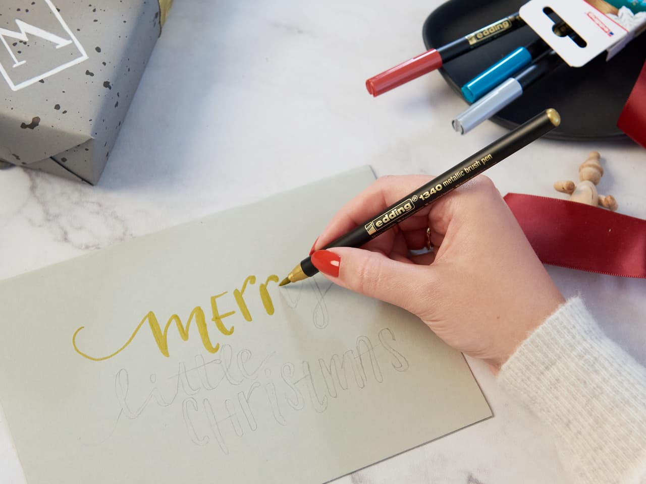 Basteln Sie eine festliche Grußkarte: „Merry Little Christmas“, handgeschrieben in Goldtinte mit edding 1340 metallic Pinselstift.