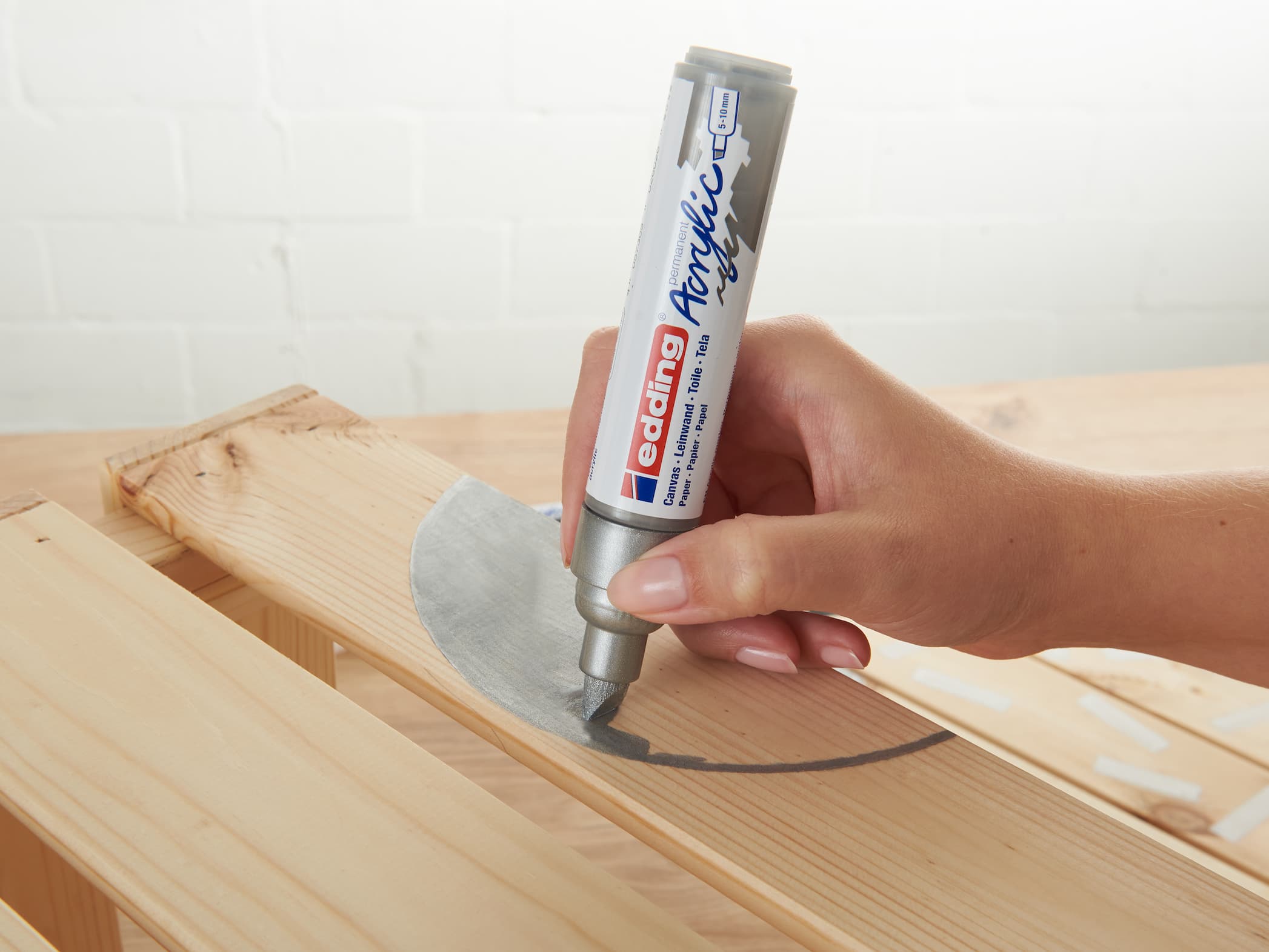 Tragen Sie den Kleber edding 5000 Acrylmarker breit aus einer Tube auf eine Holzoberfläche auf, um eine starke Verbindung zu erzielen.