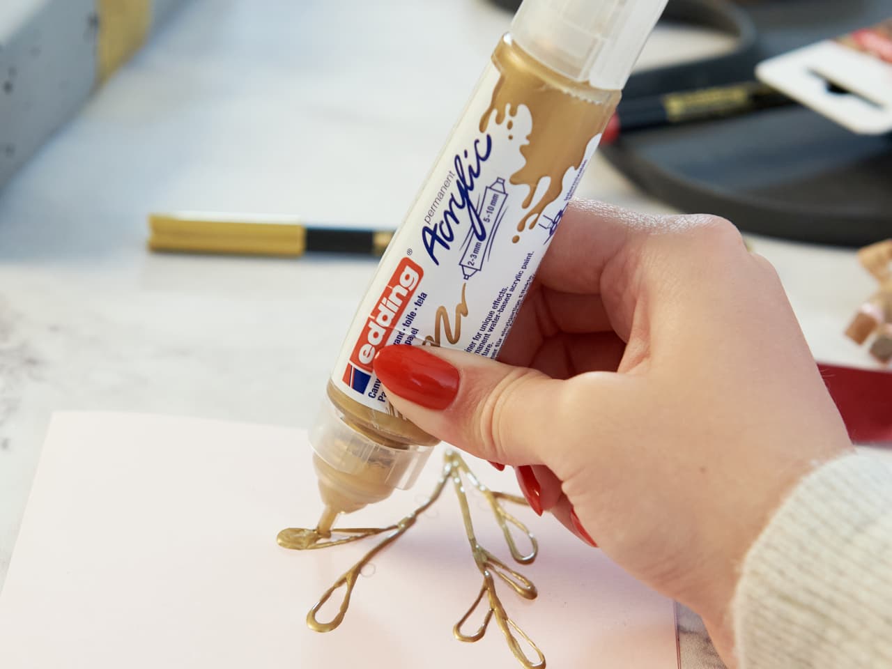 Eine Person trägt den edding 5400 Acryl 3D Double Liner aus einer Tube auf ein Blatt Papier auf.