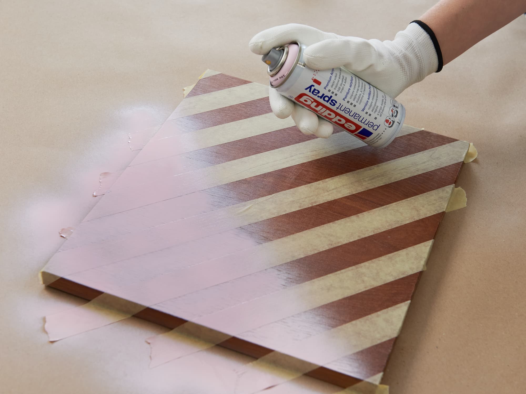 Beklebte Schranktür wird mit pastellrosa Sprühlack angesprayt