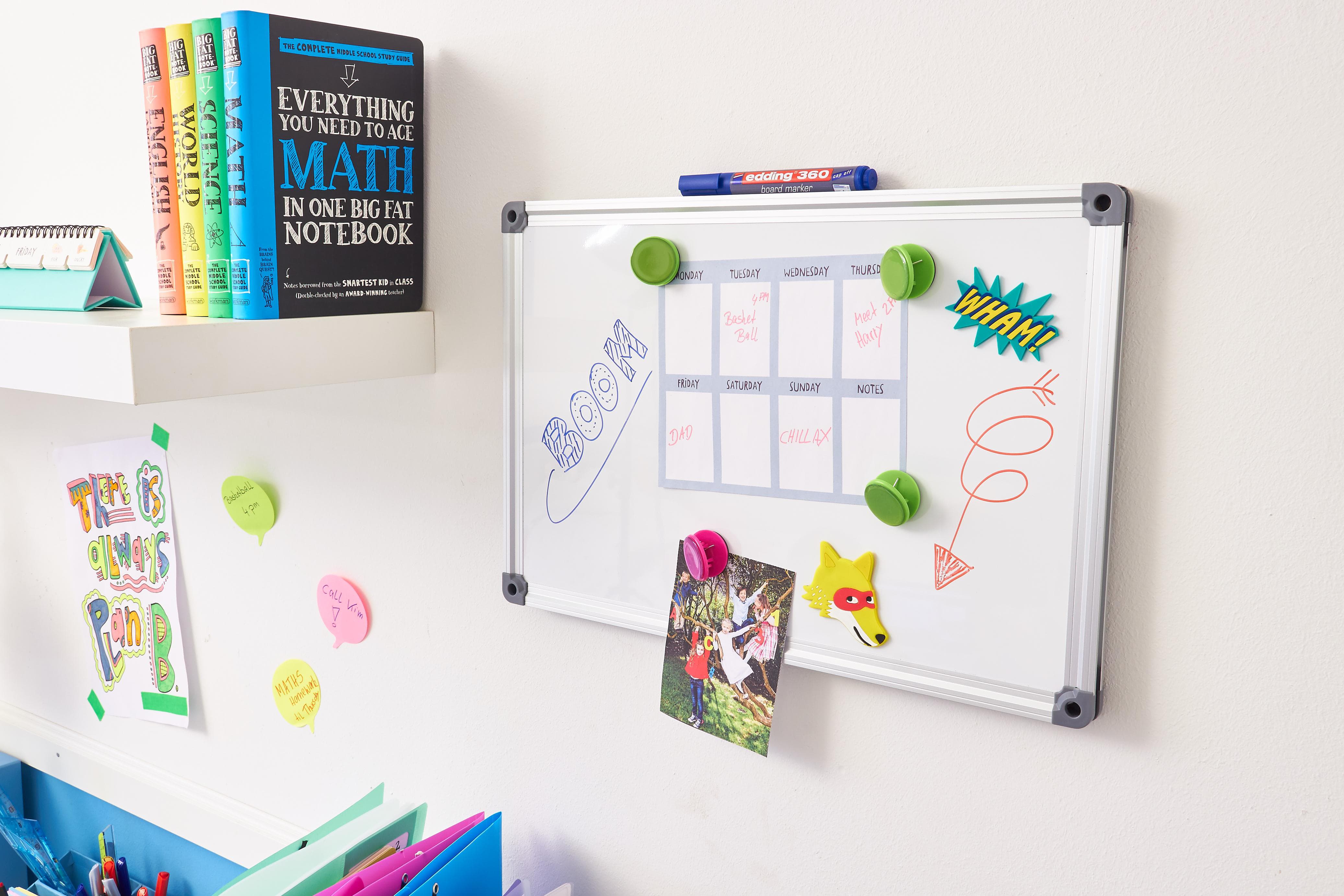 Ein lebendiger und organisierter Arbeitsbereich mit einem Whiteboard mit bunten Kritzeleien und Erinnerungen, gezeichnet mit einem edding 360 Whiteboardmarker 8er-Set, Rundspitze mittelbreit, umgeben von Haftnotizen, Büchern und Schreibutensilien.