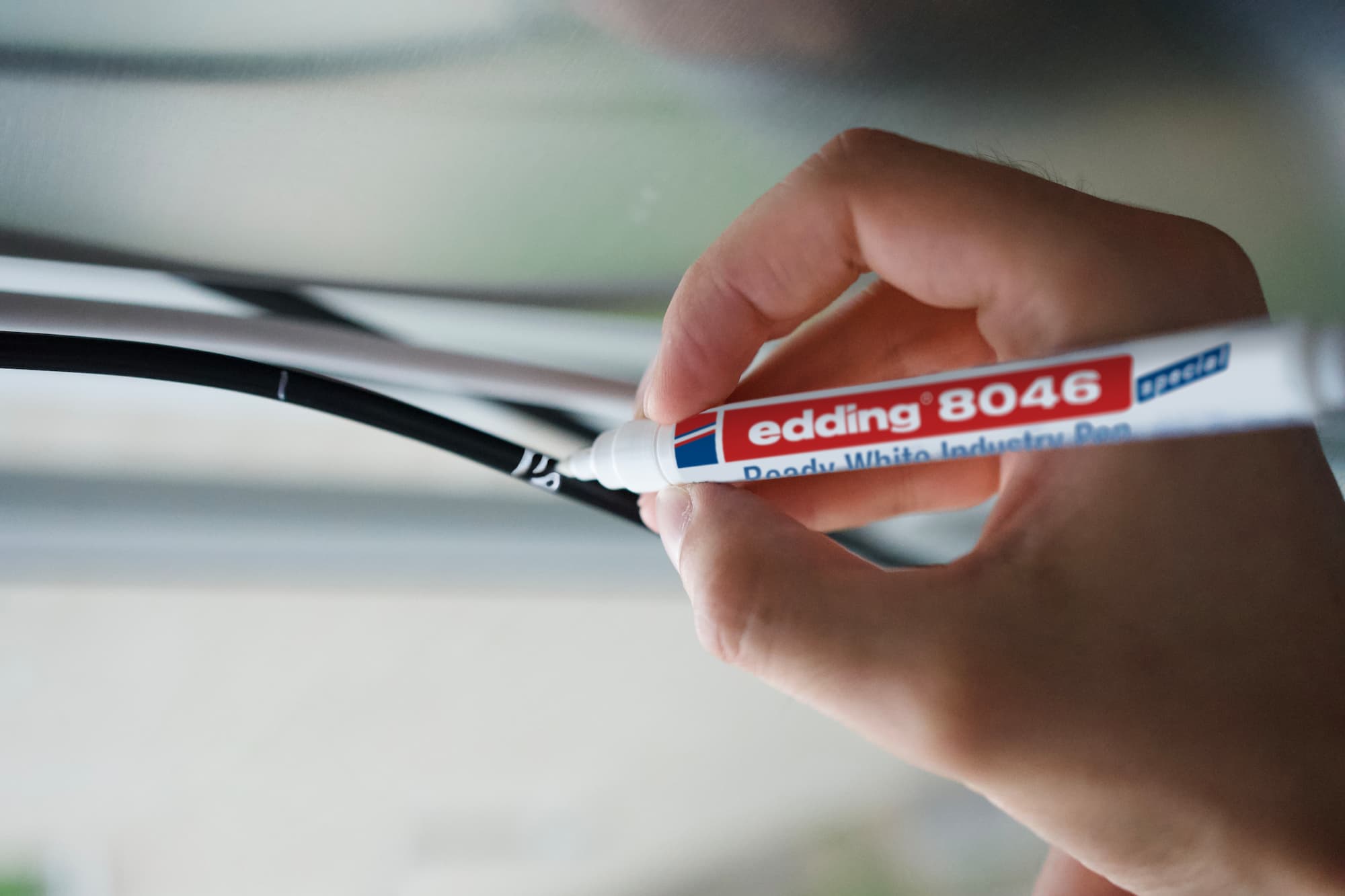 Ein edding 8046 Ready weißer Industriestift mit blauen und roten Details und schnelltrocknender Tinte, diagonal vor einem transparenten Hintergrund positioniert.