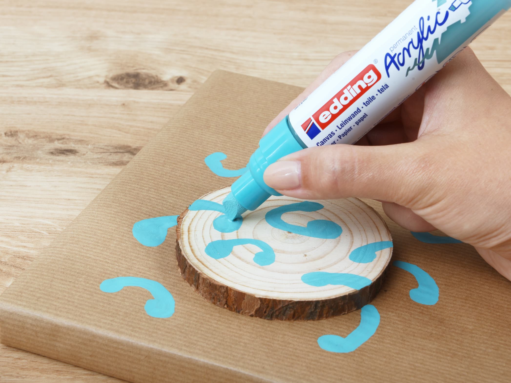 Mit einem edding 5000 Acrylmarker breit dekorative blaue Akzente auf einem Holzuntersetzer setzen.