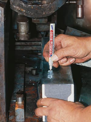 Industriemarker schreibt auf staubigem Metall