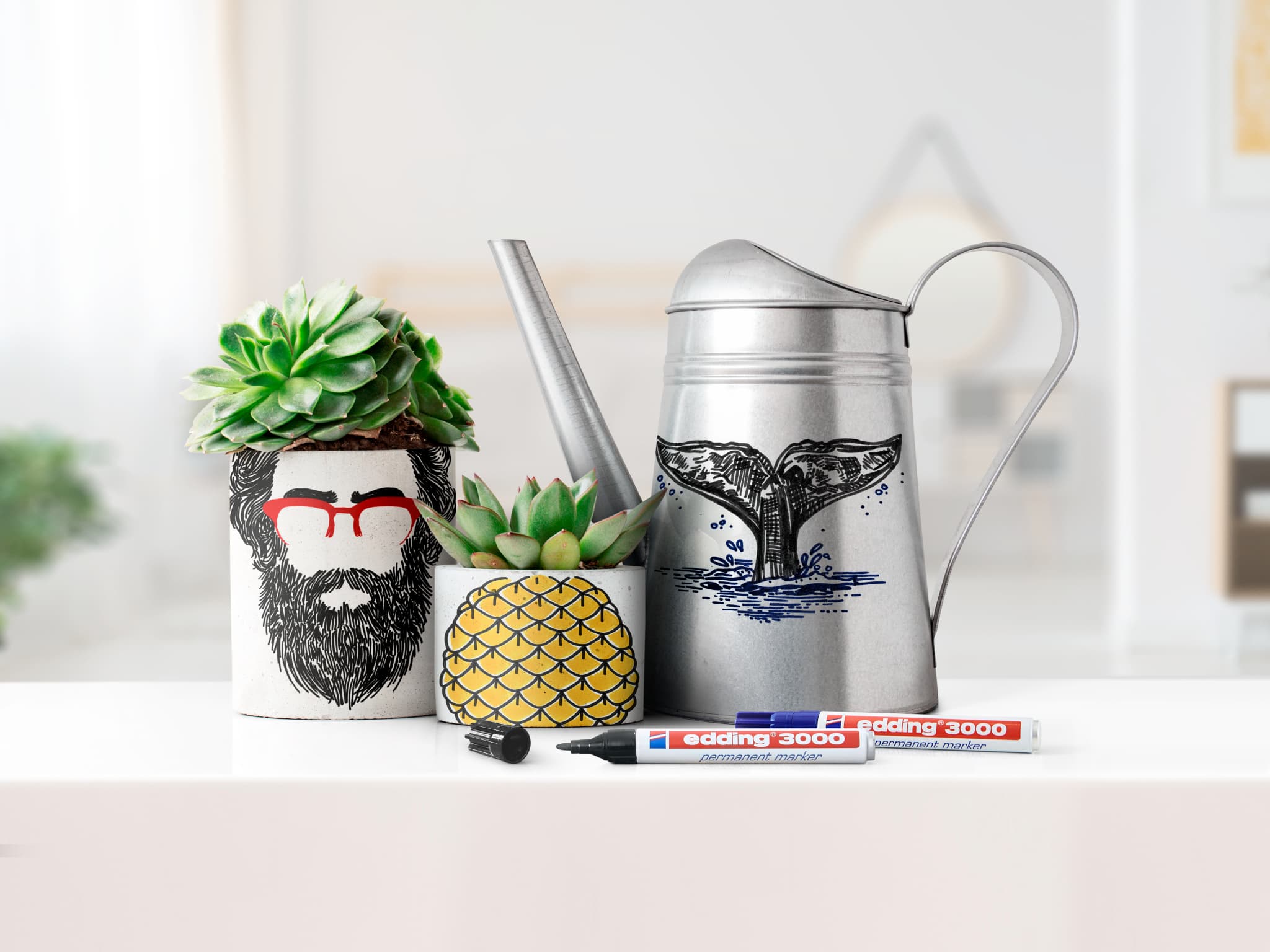 Eine gemütliche Innenszene mit einem skurrilen, bärtigen Blumentopf mit Brille, einer ananasförmigen Dekoration und einer Gießkanne mit Waldesign, begleitet von zwei edding 3000 Permanentmarkern 4er Set Made.