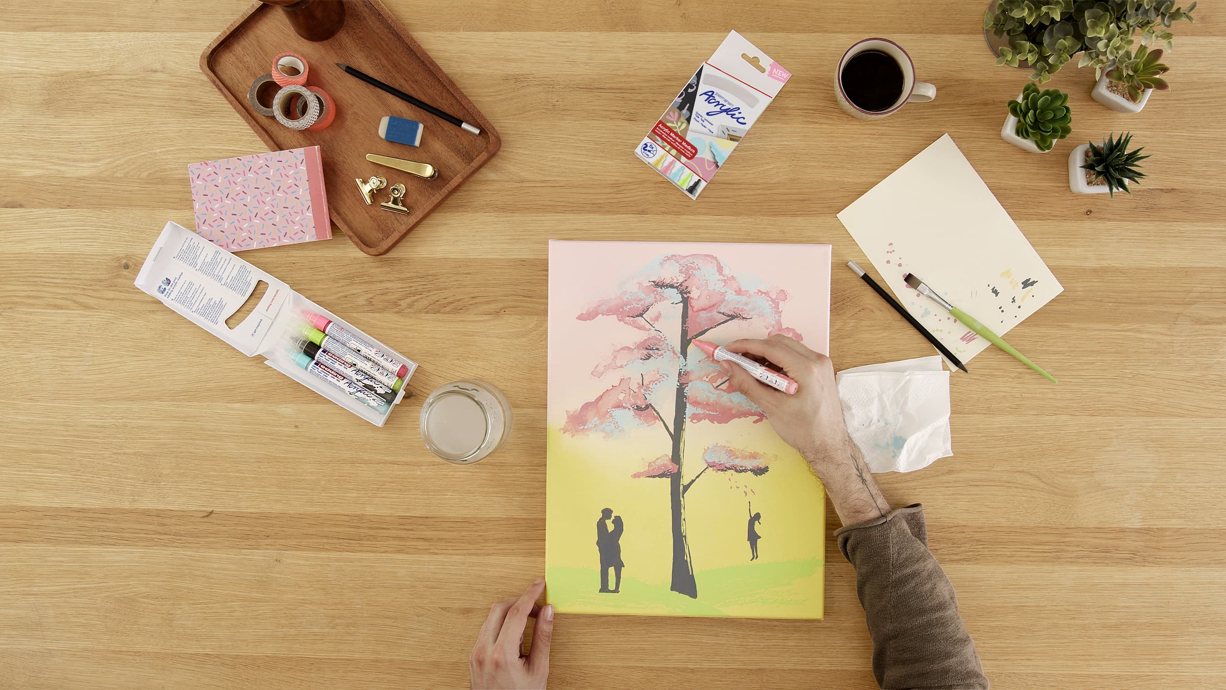 Ein Künstler gibt einem farbenfrohen Gemälde eines Baumes den letzten Schliff, indem er den kreativen Prozess mit dem Medium edding 5100 Acrylmarker auf einer Leinwand ausbreitet.