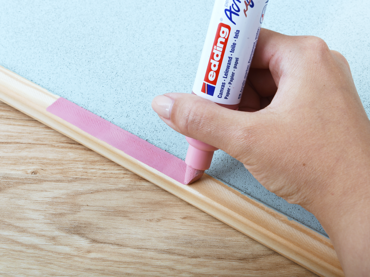 Eine Hand, die einen rosa edding 5000 Acrylmarker breit auf ein Holzbrett aufträgt.