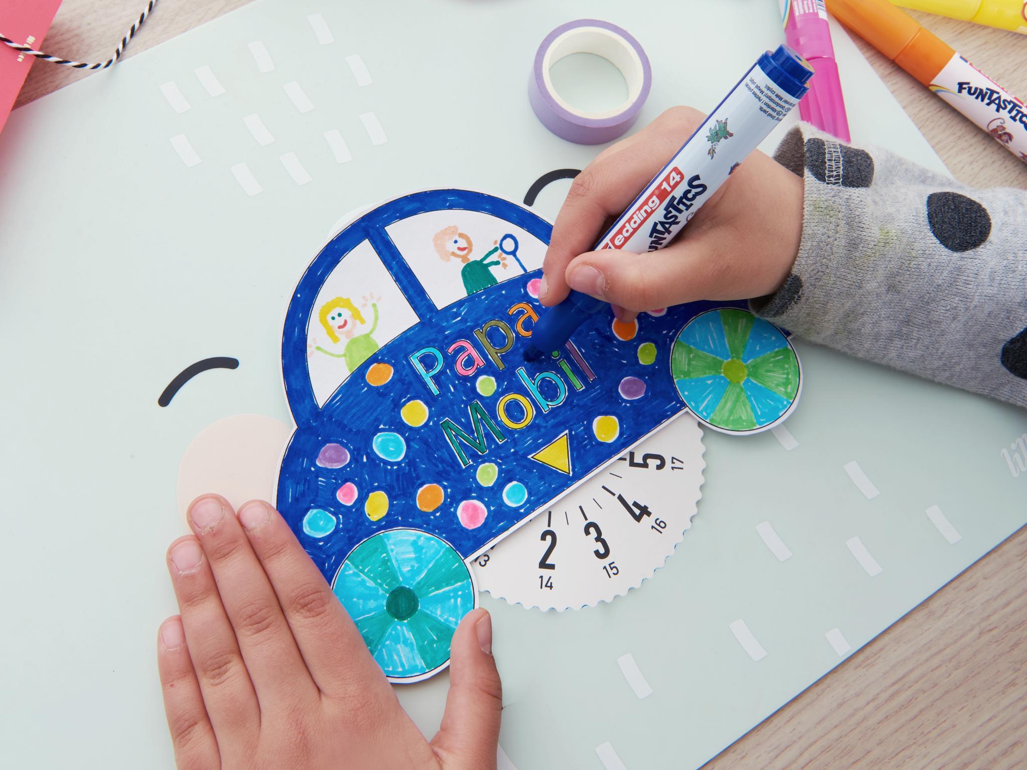 Die Hände eines Kindes fügen mit edding 14 FUNTASTICS Kinderfasermalern farbenfrohe Details zu einem handgefertigten Papierbastelprojekt mit einem skurrilen Autodesign hinzu.