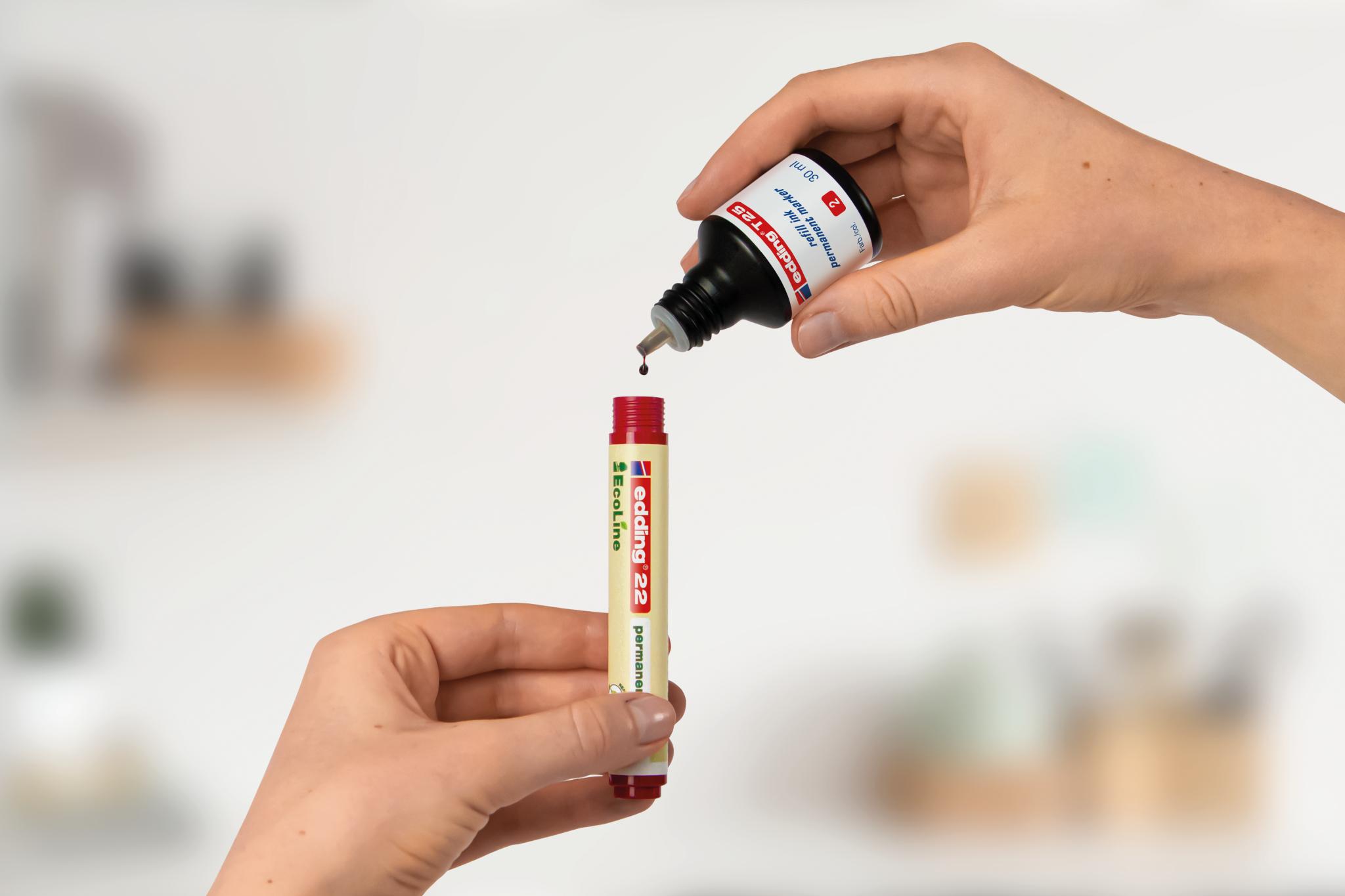 Eine kleine Menge Kleber aus einer Tube auf einen edding 21 EcoLine Permanentmarker vor einem unscharfen Hintergrund auftragen.