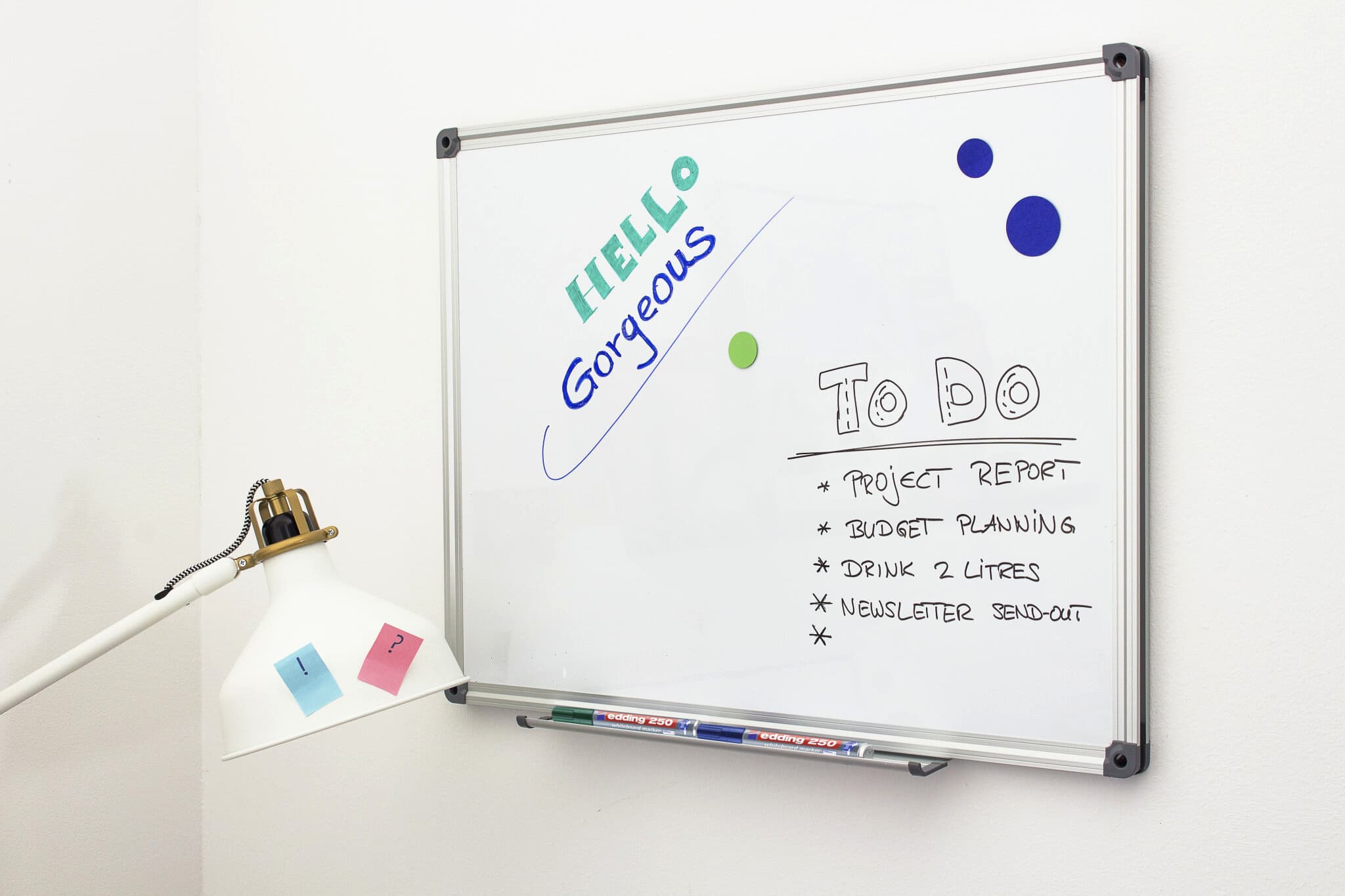Ein Whiteboard mit einer handgeschriebenen Nachricht mit der Aufschrift „Hallo Herrlich“ im farbigen edding 250 Whiteboardmarker 4er-Set, dazu eine To-Do-Liste mit Aufgaben wie Projektbericht und Budgetplanung, mit einem edding