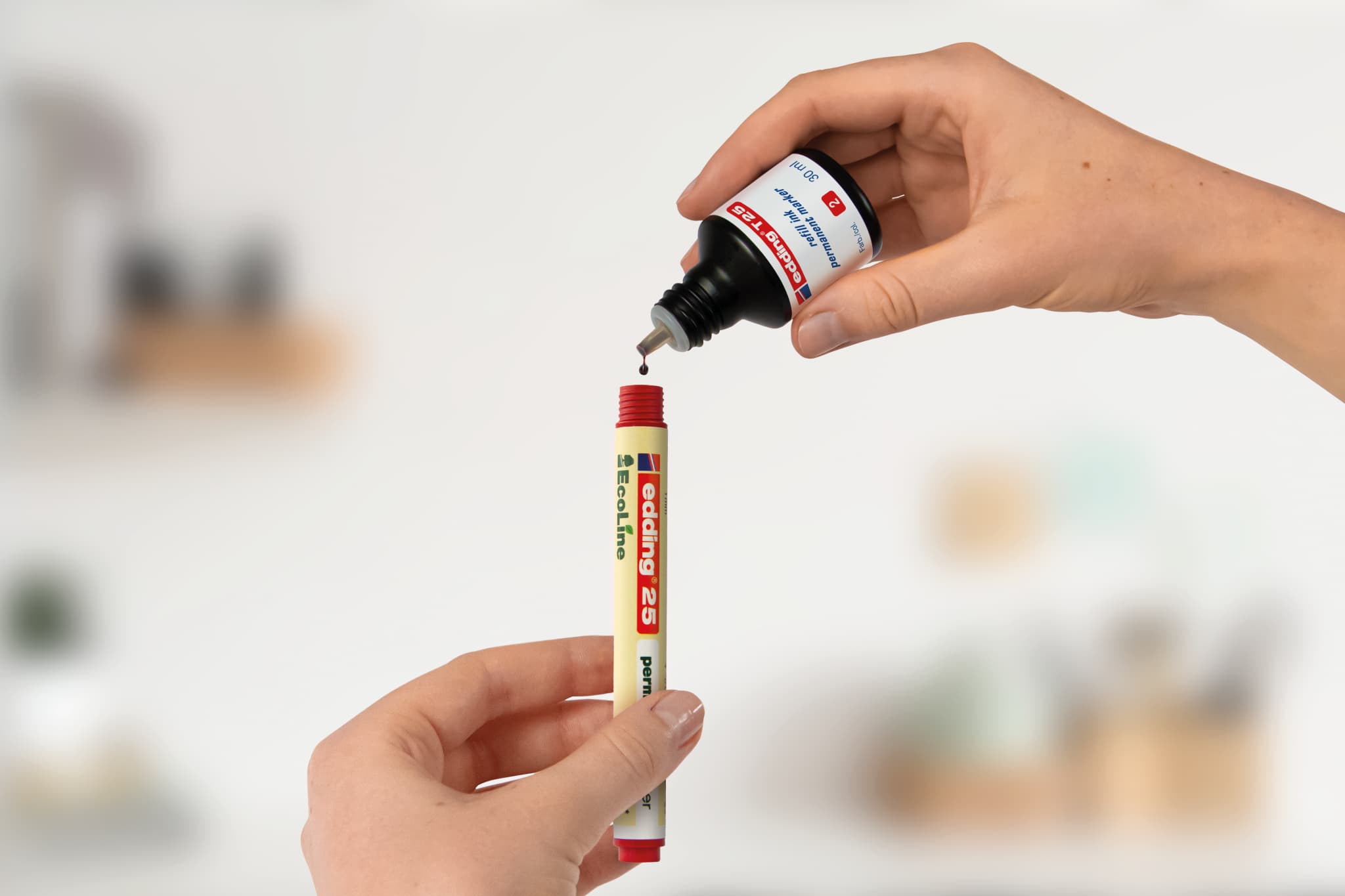 Auftragen von Klebstoff aus einer edding Ecoline-Tube in eine Klebestiftkappe.
