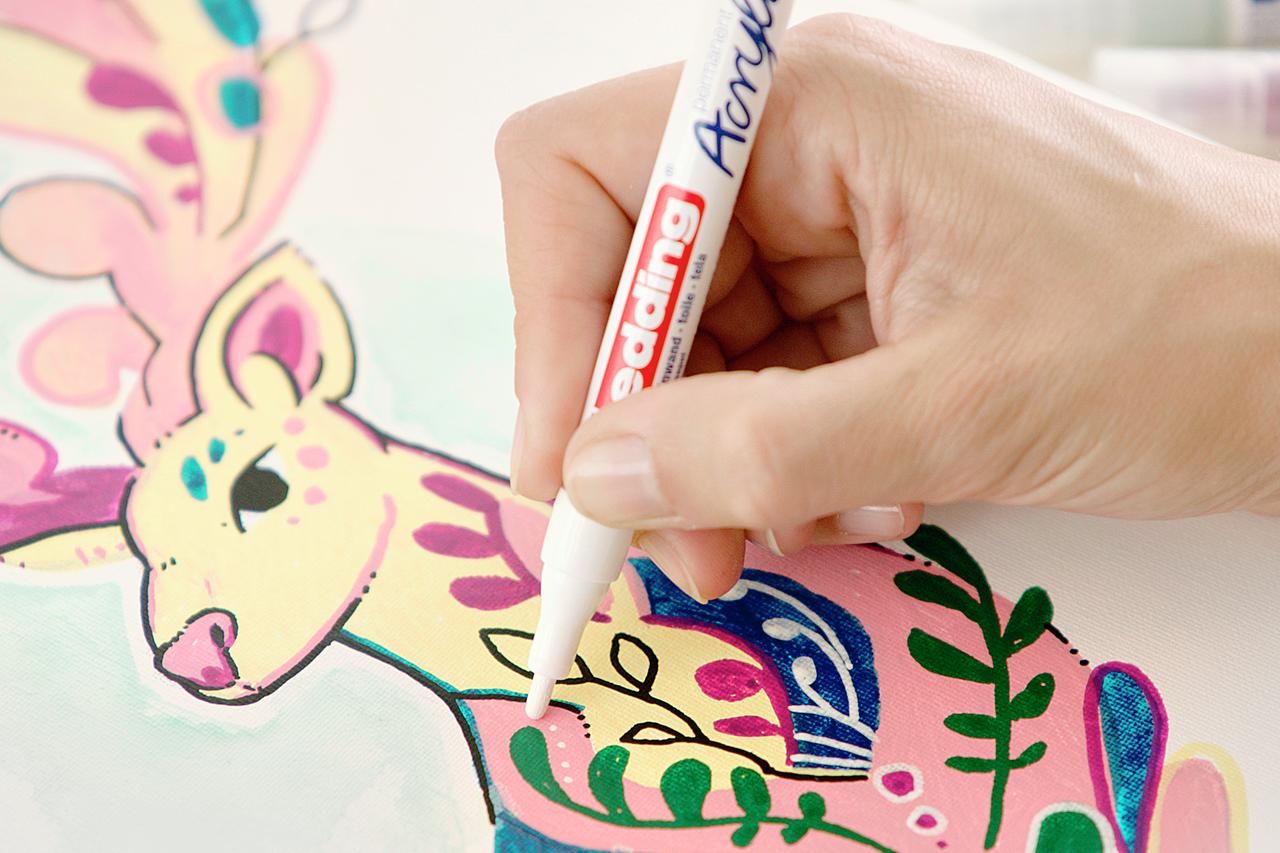 Nahaufnahme einer Hand, die eine verspielte Giraffenillustration mit einem edding 5300 Acrylmarker fein koloriert.