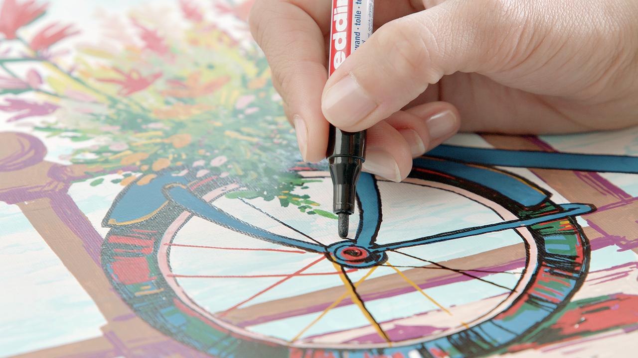 Eine Hand, die einen edding 5300 Acrylmarker fein hält und Details zu einer lebendigen, floralen Malbuchseite für Erwachsene hinzufügt.