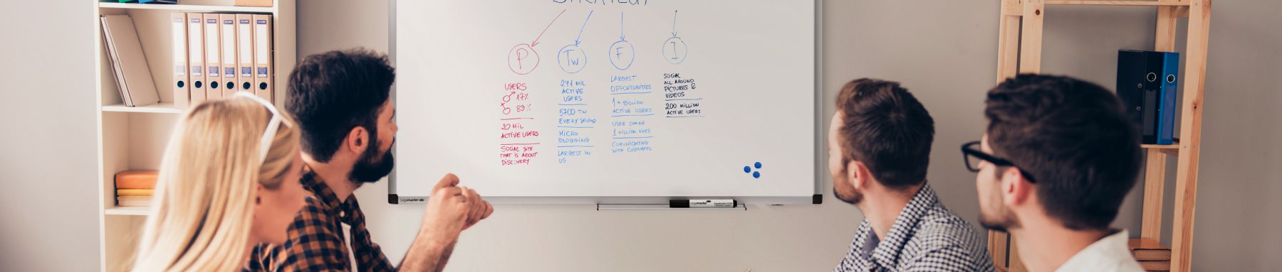 Ein Team von Fachleuten nahm an einer gemeinsamen Brainstorming-Sitzung vor einem Whiteboard mit verschiedenen Notizen und Diagrammen teil.