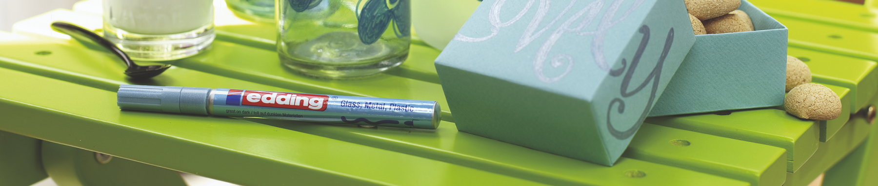 Ein markanter Moment: Auf einem leuchtend grünen Tisch quillt eine blaue Box mit einer „Dankeschön“-Nachricht über, die mit natürlichen Korkstopfen und einem rot-silbernen „edding“-Marker versehen ist.