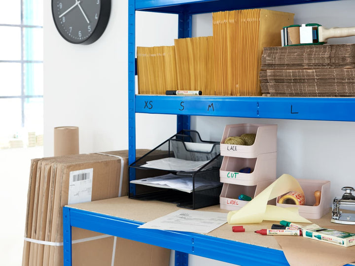 Eine organisierte Packstation mit beschrifteten Regalen, Umschlägen, Pappbögen und Verpackungsmaterialien aus recyceltem Material, bereit für das edding 21 EcoLine Permanentmarker 4er-Set.