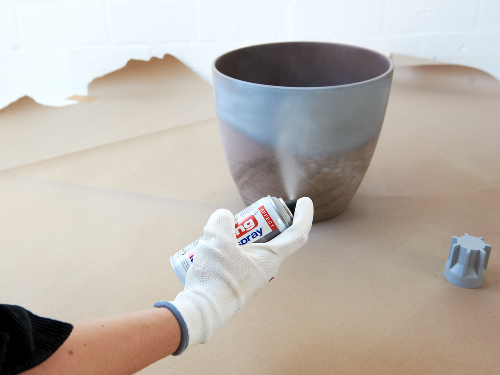 Für ein modernes DIY-Projekt können Sie mit dem edding 5200 Permanentspray Effekt Acryllack einen Keramiktopf mit einem grauen Farbverlauf besprühen.
