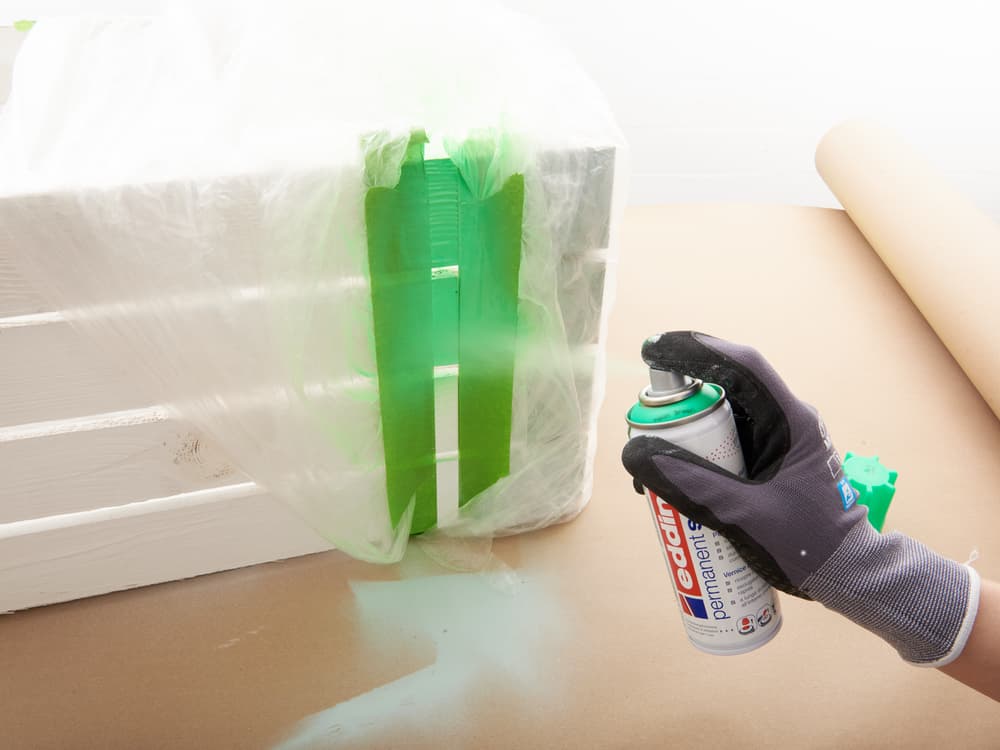 Person mit Handschuh verwendet edding 5200 Permanentspray Acryllack Neon & Kräftige Farben, um den Spalt um eine Fensterinstallation abzudichten.