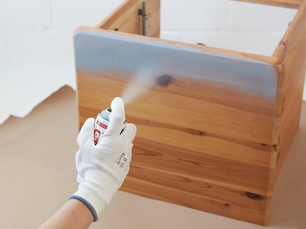 Auftragen einer schützenden edding 5200 Permanentspray Effekt Acryllack-Beschichtung auf eine Holzkiste.