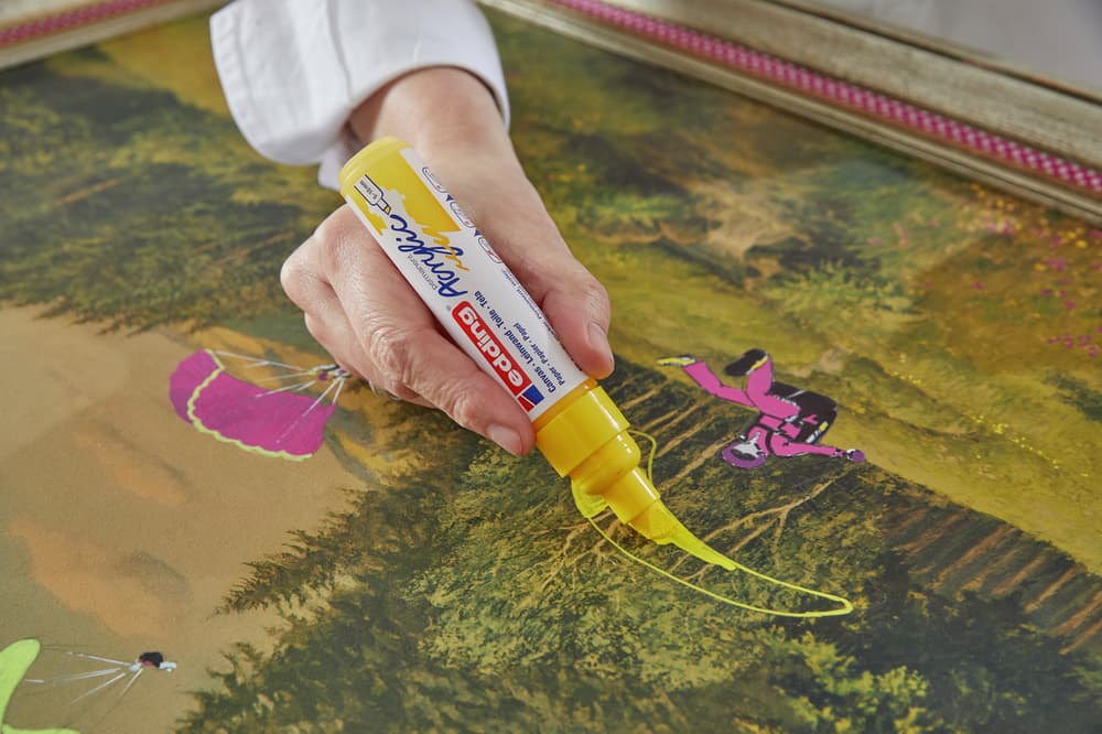 Eine Nahaufnahme der Hand einer Person, die mit einem edding 5000 Acrylmarker breit ein farbenfrohes, detailliertes Kunstwerk mit Schmetterlingsmotiven zeichnet.