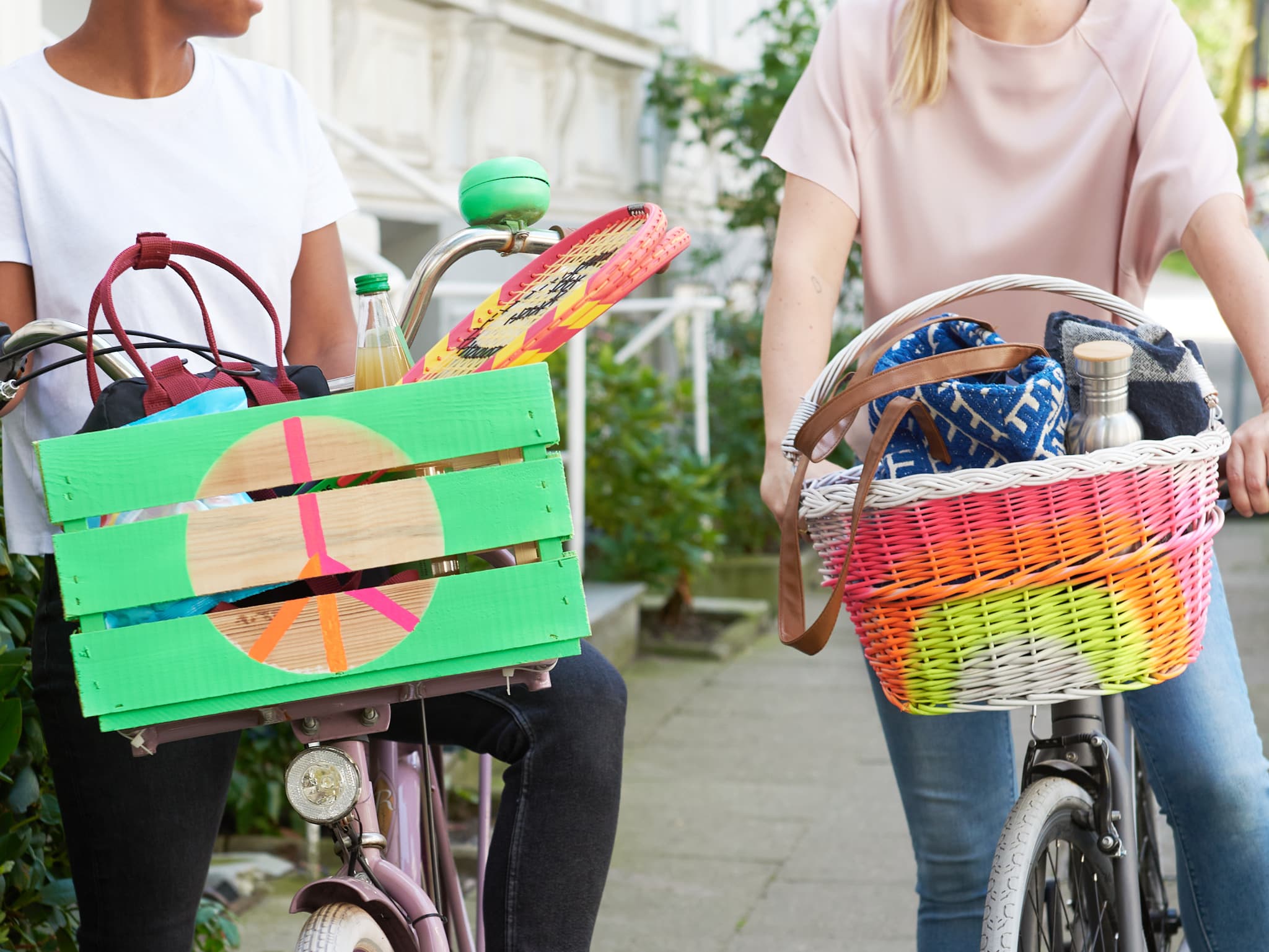 Zwei Personen auf Fahrrädern mit farbenfrohen edding 5200 Permanentspray Acryllack Neon und kräftigen Farben-Vorderradkörben genießen einen Tag im Freien.