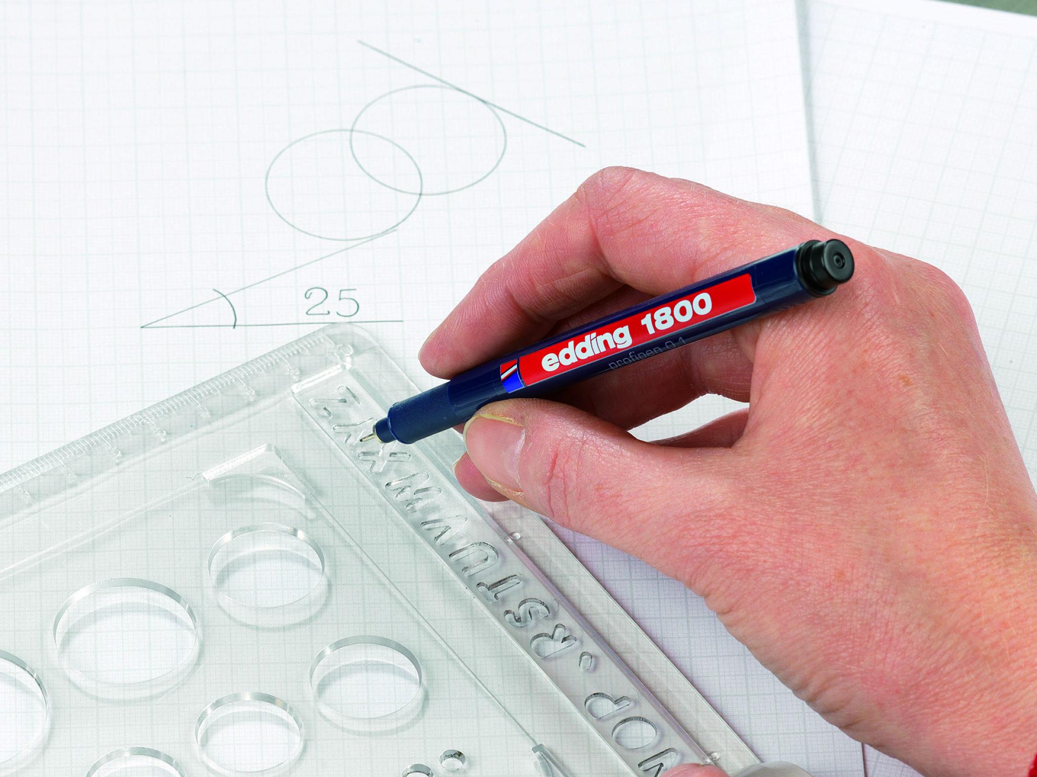 Technisches Zeichnen: Eine Hand hält einen edding 1800 Präzisionsfeinschreiber 3er-Set über ein Blatt Millimeterpapier mit geometrischen Formen und einem klaren Lineal für genaue Messungen.